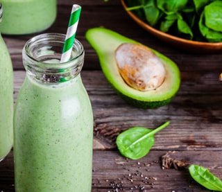 Green smoothie next to an avocado Green smoothie next to an avocado